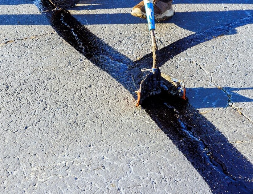 Asphalt maintenance crew sealing cracks in pavement